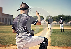 The only way to win is to start. Rearview shot of a young man giving thumbs up during a baseball match.