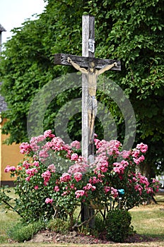 A wayside cross on a street with rose bushes in the Salzkammergut, Austria, Europe