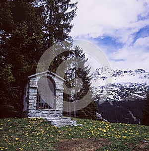 A wayside shrine on an alpine meadow near Lenzerheid, shot with slide film technique