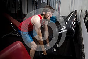 Weak man tries to lift heavy dumbbell, wants to be strong and fit. sport, motivation, strength. newbie concept in the gym