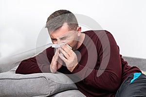 A weak and tired man blows his nose into a handkerchief.
