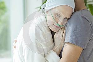 Weak woman with cancer hugging her husband during chemotherapy photo