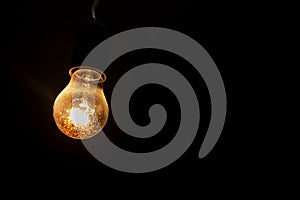 Weakly burning electric light bulb in the dark. Electricity