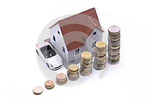 Wealth concept with house model and car near a pile ladder of money