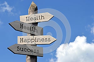 Wealth, health, happiness, success - wooden signpost with four arrows photo