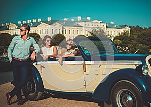 Wealthy friends near classic convertible