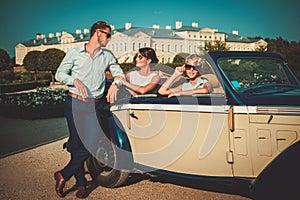 Wealthy friends near classic convertible