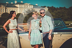 Wealthy friends near classic convertible