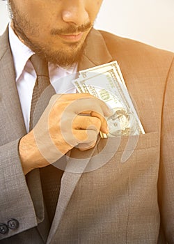 Wealthy handsome. Close-up of young man in putting money in his pocket