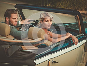 Wealthy young couple in a classic convertible