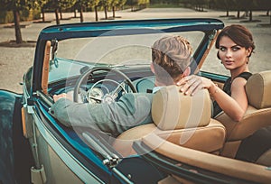 Wealthy young couple in a classic convertible photo