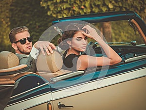 Wealthy young couple in a classic convertible