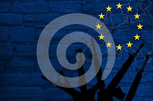 Weapons silhouettes on the background of the EU flag. Stone wall with a map of the European Union. The concept of the