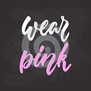 Wear pink - hand drawn October Breast Cancer Awareness Month lettering phrase on black chalkboard background. Brush ink