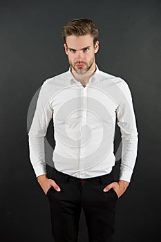 Wear it simple. White shirt and black pants. Serious man dark background. Fashion look of handsome guy. Fashion model in