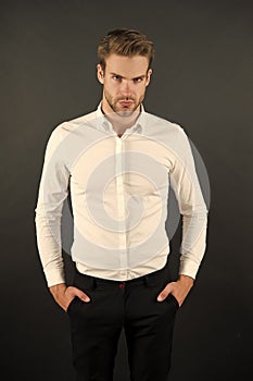 Wear it simple. White shirt and black pants. Serious man dark background. Fashion look of handsome guy. Fashion model in