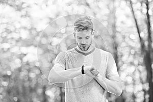 Wearable technology. Handsome athlete using smartwatch technology during training outdoor. Fit athlete tracking his