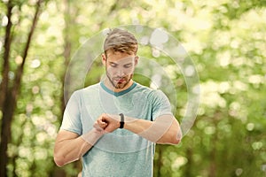 Wearable technology. Handsome athlete using smartwatch technology during training outdoor. Fit athlete tracking his