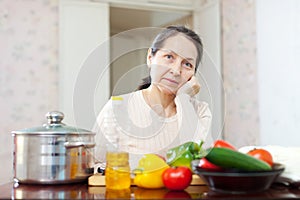 Weariness mature woman at kitchen