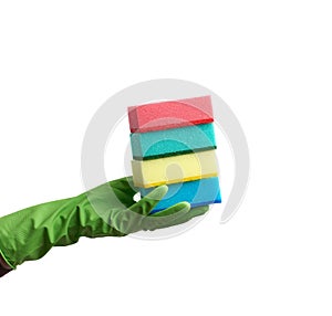 Wearing a green glove for cleaning and washing dishes, red and yellow kitchen sponges  lies in the palm of hand