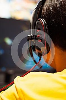 Wearing headphone, A gamer or a streamer boy at home in a room playing with friends on the networks in video games