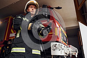 Wearing protective equipment. Woman firefighter in uniform is at work in department