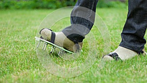 Wearing spiked lawn revitalizing aerating shoes, gardening concept