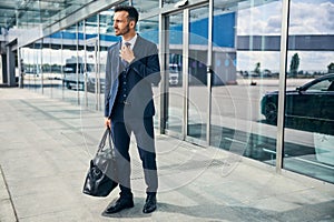 Weary-looking man exits the airport with his bag