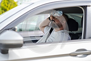 Weary overweight man drives car with broken air conditioner in hot summer weather.