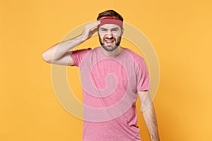 Weary sick fitness sporty guy 20s sportsman in headband t-shirt spend weekend in home gym isolated on yellow background