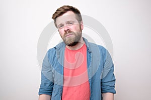 A weary, tortured young man who has a headache looks sadly with narrowed eyes.  on white background