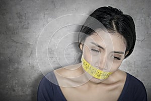 Weary woman covers her mouth with measure tape