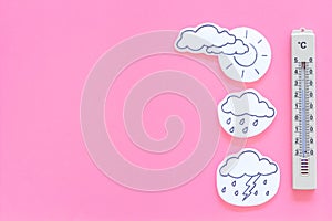 Weather forecast concept. Air temperature. Termometer among cloud and lightening, sun, rainy clouds on pink background