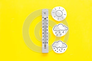 Weather forecast concept. Air temperature. Termometer among cloud, sun, rainy clouds, snow on yellow and yellow