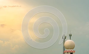 Weather observations radar dome station and telecommunication tower against blue sky and clouds. Aeronautical meteorological