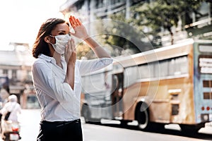 Weather, Pollution and Ecology Issue Concept. Young Woman Wearing Protection Mask against Roadside in the Urban City