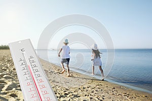 Weather thermometer and children running on sandy beach. Heat stroke warning