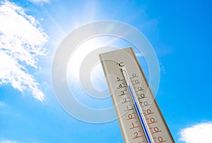 Weather thermometer with high temperature outdoors on hot sunny day. Heat stroke warning