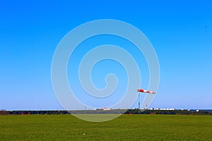 Weather vane on the airfield against the sky and green grass