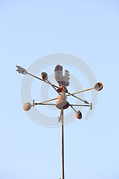 Weather Vane compass over house roof against blue sky background