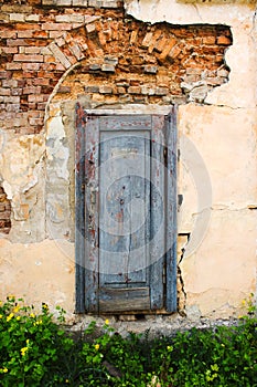 Weathered blue door with cracked paints in old city wall near abandoned palace in Busk, Western Ukraine photo