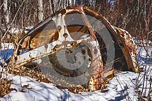 weathered car body dumped in forest in winter season