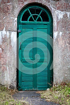 A weathered concrete outdoor underground cellar with green wooden door.