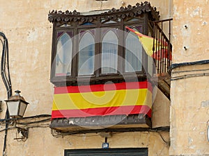 Weathered decaying balcony covered with spanish flag in Chinchon, Madrid community, Spain