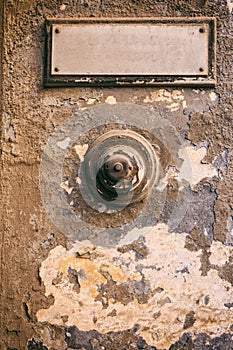 Weathered door bell and blank label on faded wall background