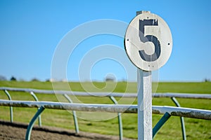 Weathered 5 furlong distance marker seen on a race course.