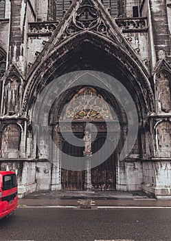 Weathered Grandeur: Close-Up of Cathedral Doors in Dinant on Rainy Day