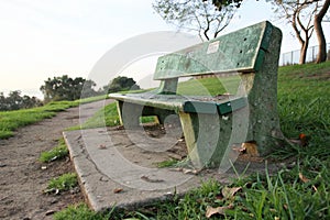 Weathered green concrete bench surrounded by grass