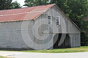 Weathered grey Amish barn with red metal roof