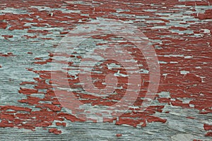 Weathered grungy peeling red paint on old grey plywood